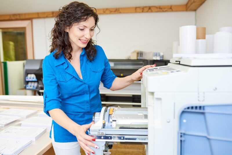 Adult woman checking printer in office