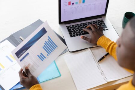 Over shoulder view of african american man using laptop and looking at spreadsheets